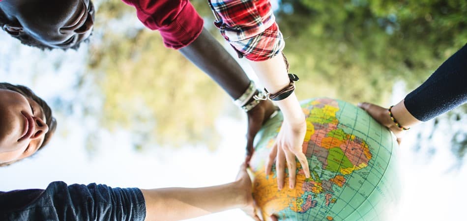 Multiple hands touching a globe.